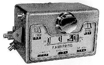 Prototyp des Taxameters EF 60: kastenförmiges Gerät mit Fahrpreisanzeige, Fenstern für Zuschlag und Taxe und einem Drehknopf.